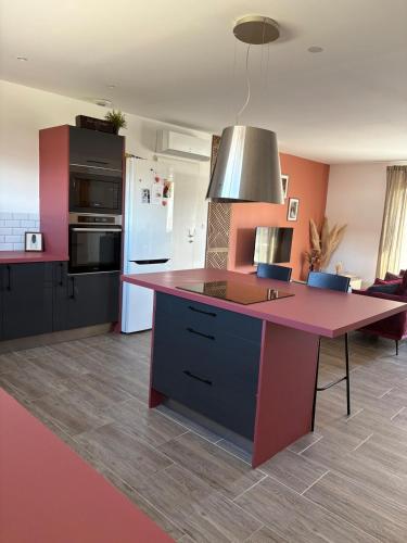 une cuisine avec une île rose au milieu dans l'établissement Villa de l olivier en Provence, à Piolenc