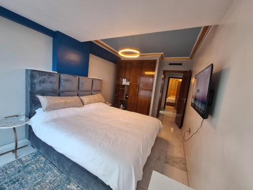 een slaapkamer met een groot bed en een flatscreen-tv bij Appartement vue Mer Tanger Boulevard in Tanger