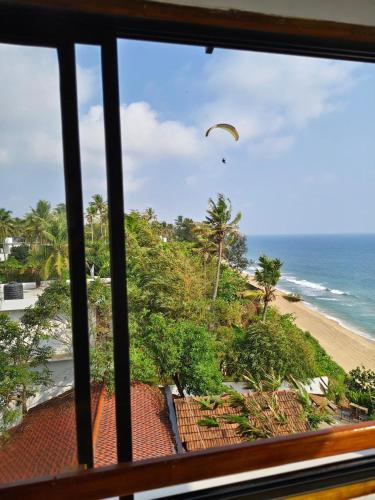 a view from a window of a beach with a parachute at Peak Paradise Resort in Varkala