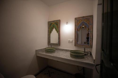 a bathroom with two sinks and two mirrors at Riad Old City Palace in Fès