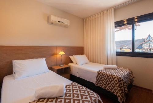 a hotel room with two beds and a window at Locar-in Gramado - Lez Lez a 30 m da Rua Coberta in Gramado