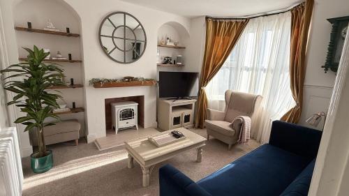 a living room with a blue couch and a fireplace at Malvern Hills House in Great Malvern
