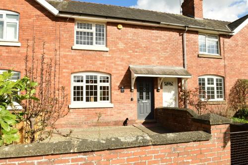 a brick house with a cat sitting in front of the door at Old Street Terrace in Ludlow