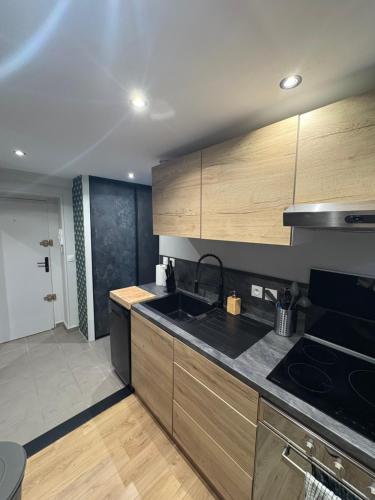 une cuisine avec des armoires en bois et un comptoir noir dans l'établissement Appartement Rouen gare/centre, à Rouen