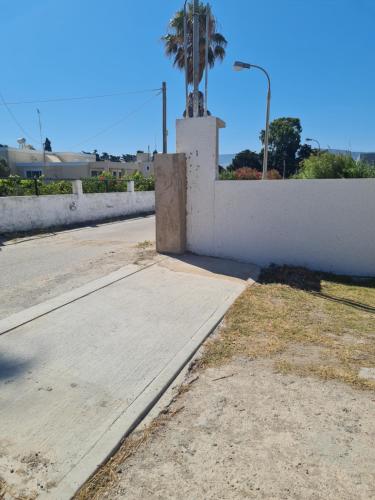 an empty street with a wall and a palm tree at Casa Di Elsa, Lambi, Kos in Kos Town