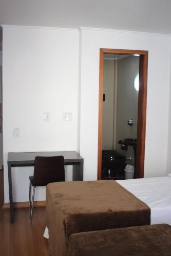 a bedroom with two beds and a desk and a chair at Letto Business in Porto Alegre