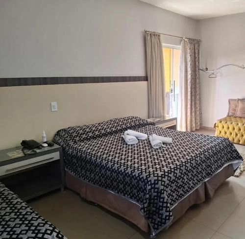 a bedroom with a bed with two shoes on it at Hotel O Recanto in Campo Mourão