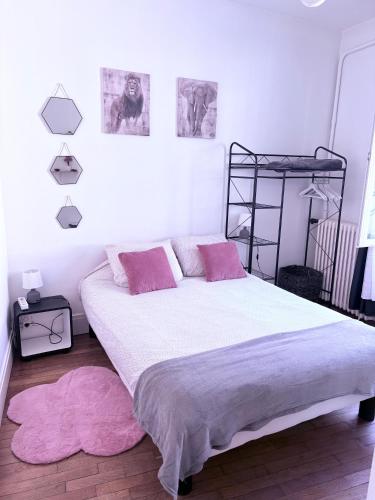 une chambre avec un grand lit blanc avec des oreillers roses dans l'établissement Très bel appartement de style ancien avec sa terrasse en bois en coeur de ville, à Compiègne