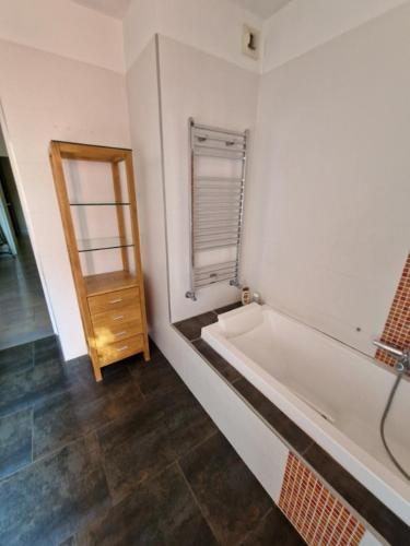 La salle de bains blanche est pourvue d'une baignoire et d'une porte en bois. dans l'établissement Villa avec piscine et dépendance, à Nîmes