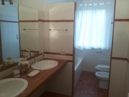 a bathroom with two sinks and a toilet and a mirror at Villa Marchetti in Cupra Marittima