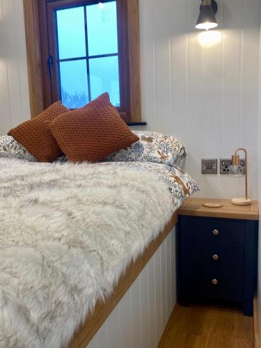 a bedroom with a bed with a night stand and a window at Aberdaron Shepherd Huts in Aberdaron