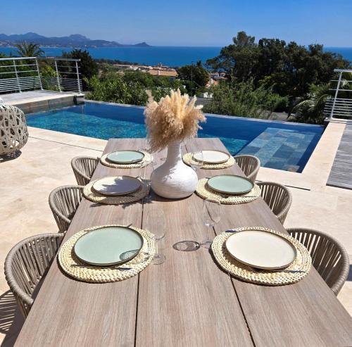 a wooden table with plates and a vase on it at Villa Bali, magnifique vue mer et Esterel in Saint-Aygulf