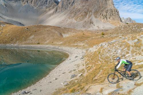 a man riding a bike on a hill next to a lake at Chalet d'alpage au coeur du Parc naturel du Queyras - exceptionnel in Valpreveyre