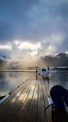 a person standing on a dock with a plane on the water at Cozy Spacious Retreat with Fireplace 205 in Juneau