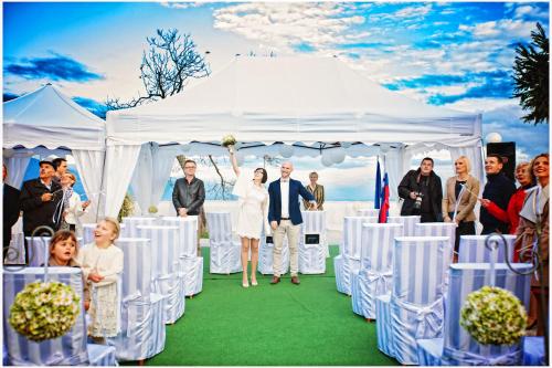 a bride and groom walking down the aisle in a white tent at Hotel Bellevue in Kranj