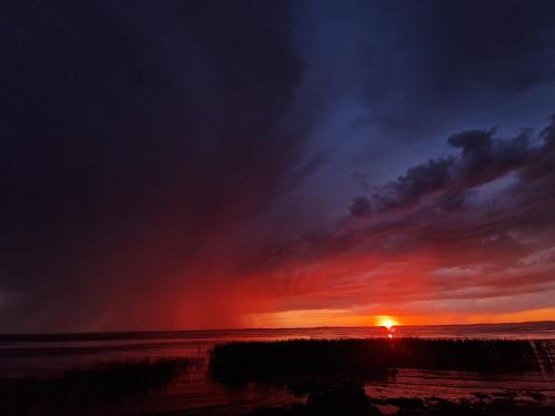 a sunset on the beach with the sun setting at Pieninė in Ventė