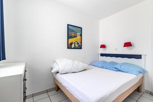 - une chambre blanche avec un lit et des oreillers bleus dans l'établissement Résidence Port Bourgenay - maeva Home - Appartement 2 pièces 4 personnes - Sélection MAE-8921, à Saint-Hilaire-de-Talmont