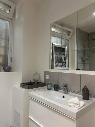 une salle de bain blanche avec un lavabo et un miroir dans l'établissement Le pétillant - cathédrale, à Reims