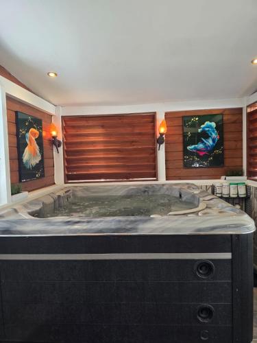 a large bath tub in a room with paintings at Appartement Bella in Vieux Bourg