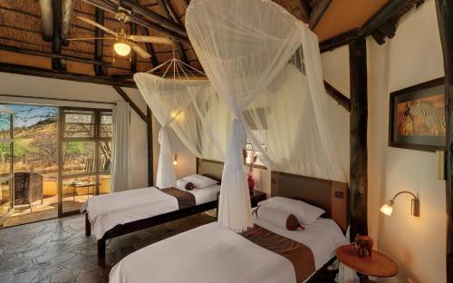 a bedroom with three beds with mosquito nets at Immanuel Wilderness Lodge in Windhoek