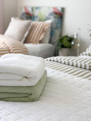 a pile of towels sitting on top of a bed at Tropicana Bijou - Studio & Spa in Carters Beach