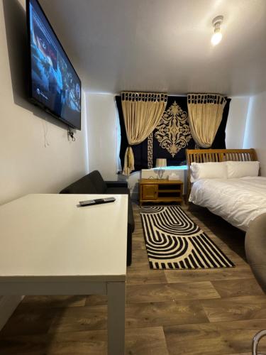 a room with a bed and a table and a tv at OYO Unique Guestroom - Farnworth, Easy Access to Bolton in Farnworth