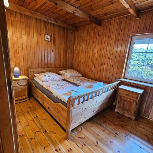 a bedroom with a bed in a wooden room at Domek Malina in Nadole