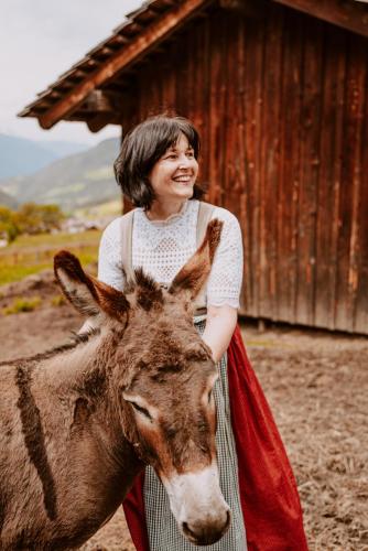 a woman is standing next to a donkey at Hotel Bergschlössl in Luson
