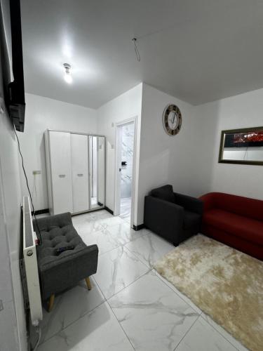 a living room with a red couch and a chair at OYO Unique Guestroom - Farnworth, Easy Access to Bolton in Farnworth