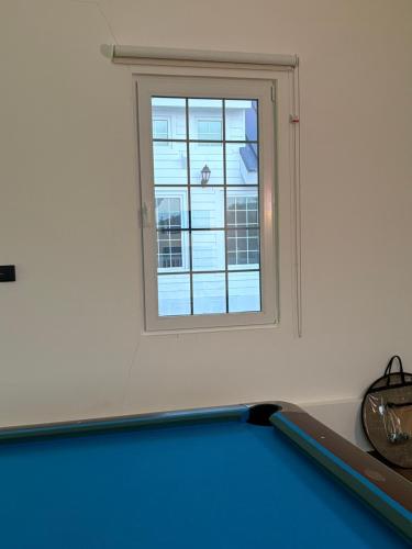 a ping pong table in a room with a window at Prairie in Al Khaznah