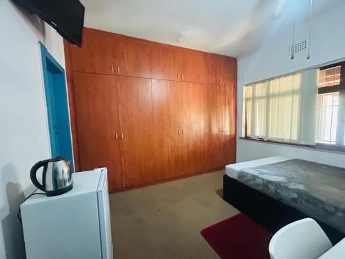 a bedroom with a bed and wooden cabinets at Executive Accommodation Bellville 2 in Cape Town