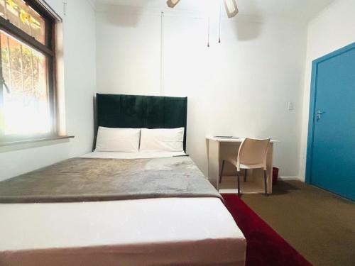 a bedroom with a bed and a table and a window at Executive Accommodation Bellville 2 in Cape Town