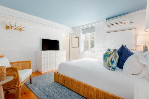 a white bedroom with a bed and a tv at Anchor Inn in Nantucket