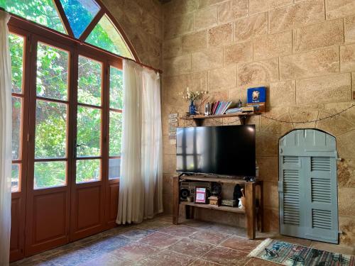 een woonkamer met een tv en een groot raam bij Beit Tout Guesthouse in Saïda