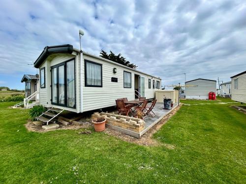 a small white house with a picnic table in a yard at VerbLake 5 Berth Caravan St Osyth Beach Holiday Park in Saint Osyth