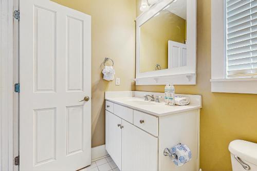 Un baño con un lavabo blanco y un espejo. en Barefoot Cottages #B16, en Highland View