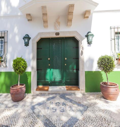 a green door with two potted trees in front of it at Villa Estefânia, Sintra in Sintra