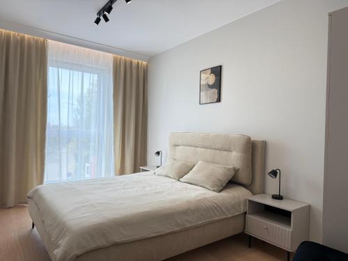 a bedroom with a bed and a large window at Apartamenty Klonova Park in Olecko