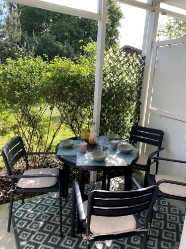 une table et des chaises assises sur une terrasse couverte avec une table et des chaises dans l'établissement Joli appartement à Andernos les bains , 2 ou 4 pers , avec terrasse et parking, à Andernos-les-Bains