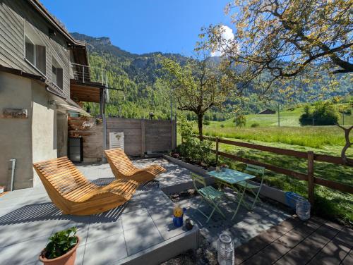 a patio with two chairs and a glass table at Mitten in den Glarner Alpen Hot Tub & Alpenblick in Ennenda