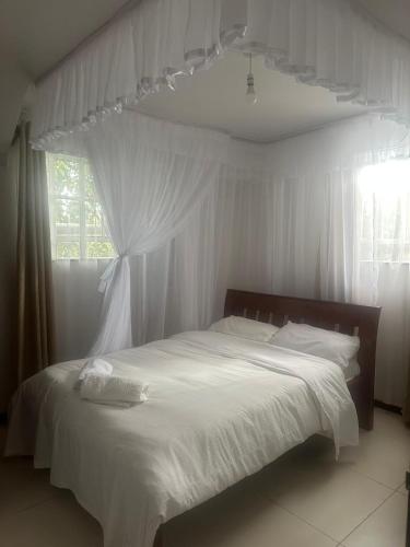 a bedroom with a bed with white sheets and a window at Gerbera staycation in Nairobi