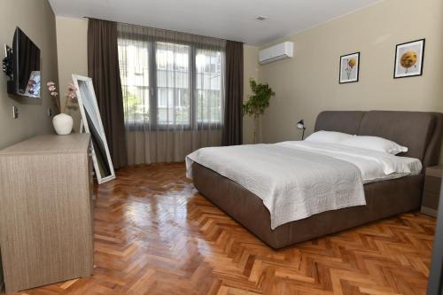 Un dormitorio con una cama grande y suelo de madera. en Апартамент Инфинити, en Veliko Tŭrnovo