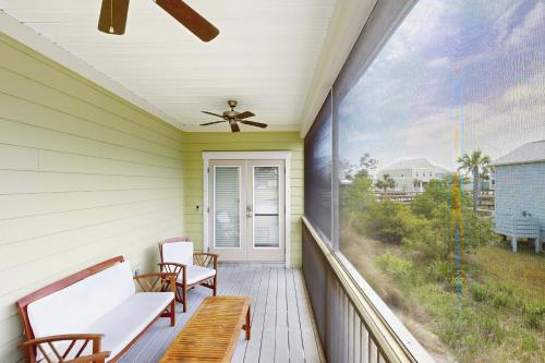 a porch with two chairs and a ceiling fan at Windmark The Oz of Windmark Beach in Highland View