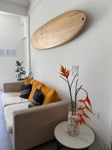 a living room with a couch and a surfboard on the wall at Si! Coral Inn in Thulusdhoo