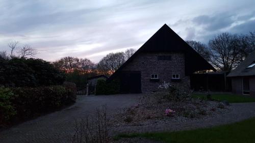 a brick house with a black roof in a yard at Boerderij de Borgh in Westerbork