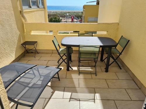 un patio avec une table et des chaises sur un balcon dans l'établissement Appartement 2 chambres vue mer, à Leucate-Plage