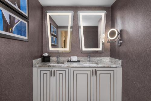 a bathroom with two sinks and two mirrors at The Jung Hotel and Residences in New Orleans