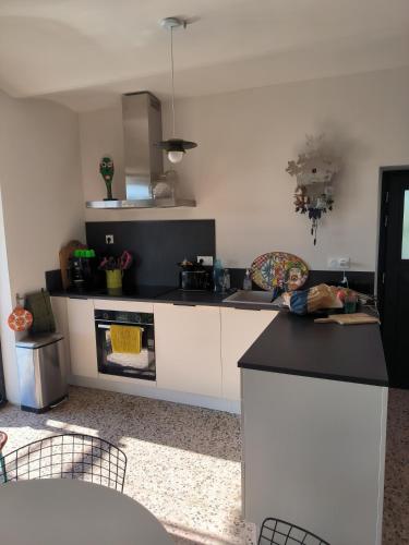 une cuisine avec des armoires blanches et un four à plaques de cuisson dans l'établissement Charmant lavilledieu, à La Celle-sous-Gouzon