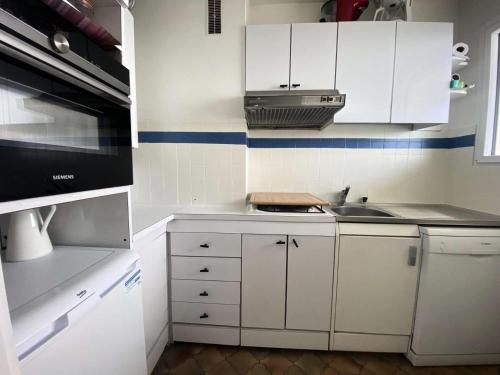 une petite cuisine avec des armoires blanches et un évier dans l'établissement Résidence Les Goëlands - T1 vue mer, emplacement idéal près du centre MAE-9474, à Arcachon
