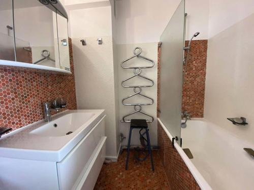 La salle de bains est pourvue d'un lavabo et d'un porte-serviettes à côté d'une baignoire. dans l'établissement Résidence Les Goëlands - T1 vue mer, emplacement idéal près du centre MAE-9474, à Arcachon